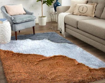 May include: A fluffy, brown, white, and gray area rug with a wavy design. The rug is in a living room setting with a couch and a chair.