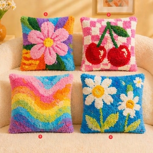 May include: Four decorative throw pillows with colorful, textured designs. One features a pink flower, another cherries on a pink and white checkered background, a third has a rainbow pattern, and the last has white daisies on a blue background.