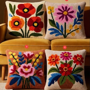 Pode incluir: Quatro almofadas quadradas com desenhos florais. Cada almofada apresenta um arranjo floral colorido diferente, incluindo papoilas, margaridas e outras flores, sobre um fundo neutro. As almofadas estão dispostas num sofá amarelo.