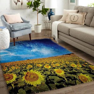 Puede incluir: Una alfombra azul y amarilla con un campo de girasoles y un cielo azul con nubes en el fondo.