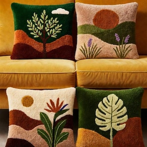 Könnte beinhalten: Vier dekorative Zierkissen mit Naturmotiven. Jedes Kissen zeigt eine andere Landschaftsszene, darunter Bäume, Sonnen und Pflanzen, in Grün-, Braun- und Cremetönen. Die Kissen sind quadratisch und haben eine strukturierte Optik.