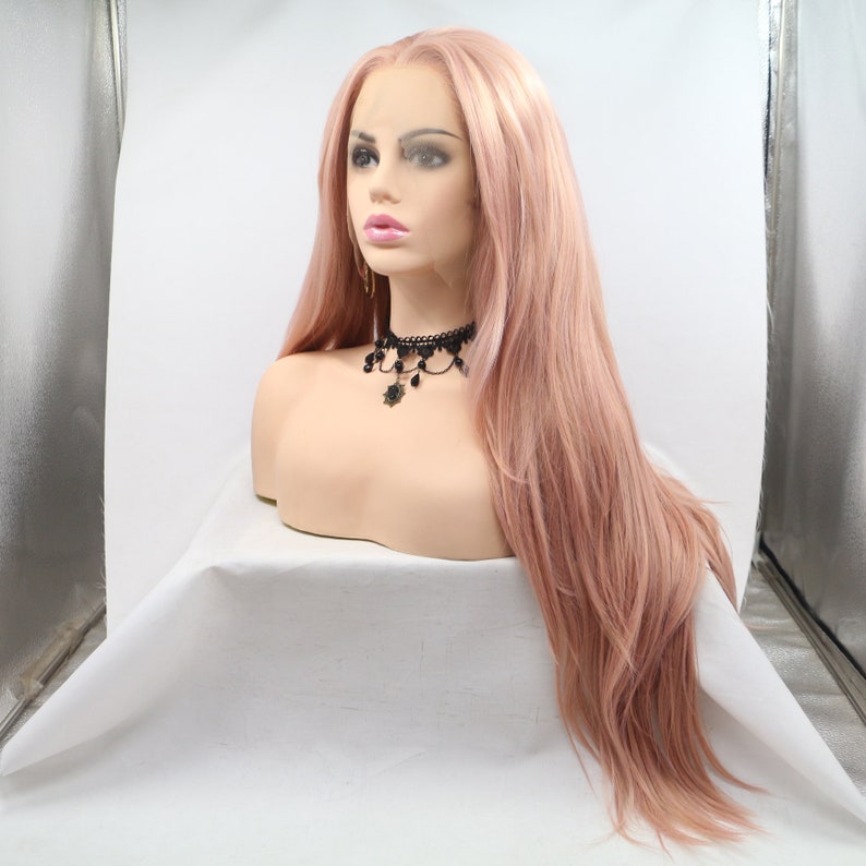 May include: A long, straight, light pink wig with a lace front. The wig is styled with soft waves and is worn on a mannequin head.