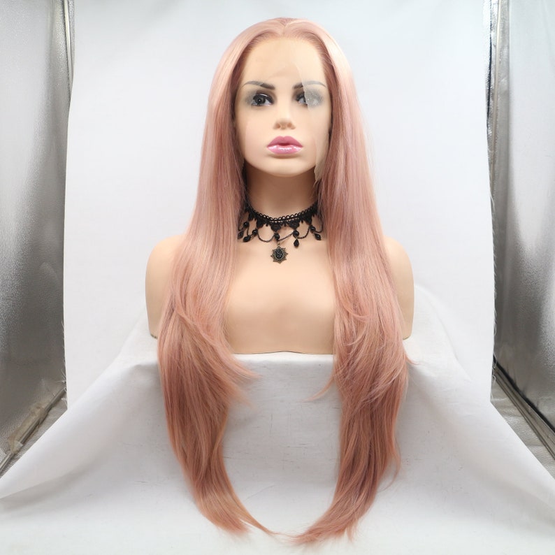 May include: A long, straight, light pink wig with a lace front. The wig is styled with soft waves and is worn on a mannequin head.