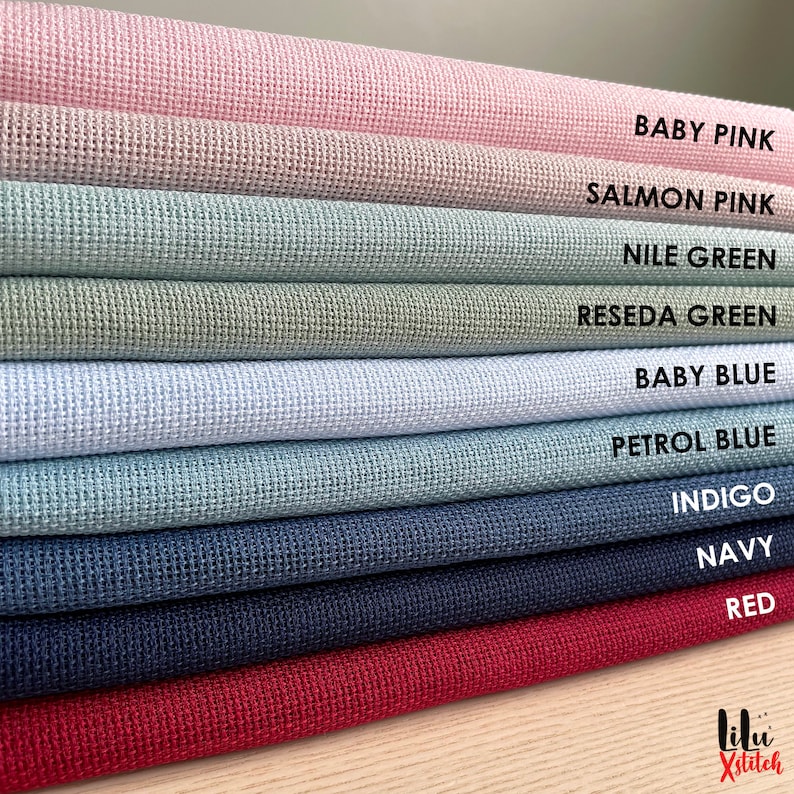 Pu&ograve; includere: Una pila di 10 tessuti Aida di diversi colori per ricamo a punto croce. I colori sono rosa tenue, rosa salmone, verde Nilo, verde reseda, azzurro, blu petrolio, indaco, blu navy e rosso.