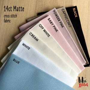 May include: A variety of 14 count Aida cloth fabric swatches in colors including black, cappuccino, powder pink, baby pink, off white, cream, white, and blue. The fabric is labeled "14ct Matte cross stitch fabric".