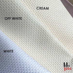 May include: Close-up of three fabric swatches in white, off-white, and cream. The fabric has a textured weave. The swatches are labeled "WHITE", "OFF WHITE", and "CREAM".