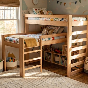 Puede incluir: Una litera de madera clara con una escalera y estanterías empotradas. Las camas están hechas con ropa de cama estampada y almohadas. La habitación tiene una alfombra, juguetes y una ventana.