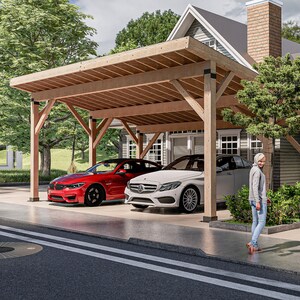 May include: A wooden carport with a pitched roof provides shelter for two cars, a red car and a white car. The carport is attached to a house with grey siding and a brick chimney. A person is walking towards the house.