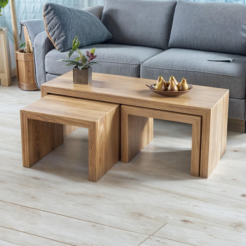 Puede incluir: Un conjunto de tres mesas de centro de madera encajables. La mesa m&aacute;s grande est&aacute; en el centro, con dos mesas m&aacute;s peque&ntilde;as encajadas debajo. Las mesas est&aacute;n hechas de madera marr&oacute;n claro con veta natural.
