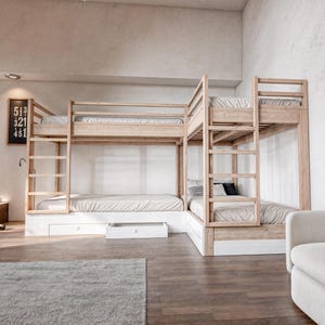 May include: A wooden bunk bed with four beds, two on each level. The bed has a white and light wood finish. The bed has a ladder on the side and a drawer underneath the bottom bunk.