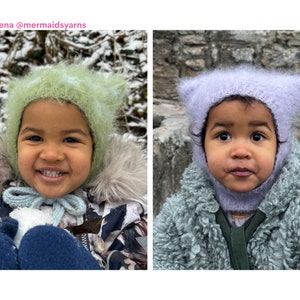 May include: Two children wearing handmade, fluffy winter hats. One child is wearing a light green hat and the other a lavender hat. The hats have a cat-ear design. The children are wearing winter coats.