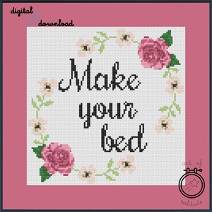 Könnte beinhalten: Kreuzstichmuster mit einem Blumenkranz und dem Text "Make your bed" in schwarzer Kursivschrift. Das Muster ist auf weißem Hintergrund mit rosa Rand.