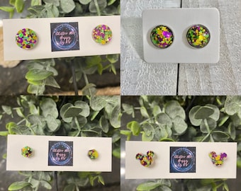 May include: Four sets of earrings featuring green, purple, and gold glitter. The earrings are displayed on white cards with the text "Glitter Me Happy by KT".