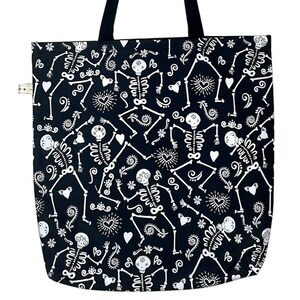 May include: Black tote bag with a white skeleton pattern. The skeletons are dancing and have flowers and hearts around them.