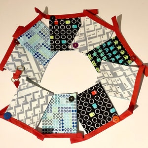 May include: A red, white, and blue fabric bunting with a keyboard, Pac-Man, and maze pattern. The bunting is made of eight flags with red stitching and white buttons.