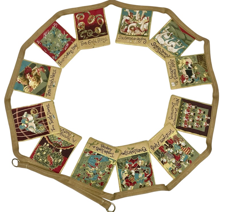 May include: A fabric garland with 12 colorful pennants featuring illustrations and text from the song "The Twelve Days of Christmas". Each pennant has a different verse of the song, such as "Two Turtle Doves" and "Five Gold Rings".