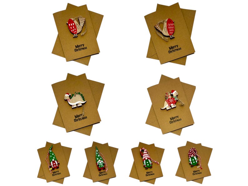 Op de afbeelding: Een verzameling kerstkaarten van kraftpapier met houten ornamenten. Elke kaart heeft een uniek ornament, waaronder een vogel, een dinosaurus en een kabouter. De woorden "Merry Christmas" staan op elke kaart.