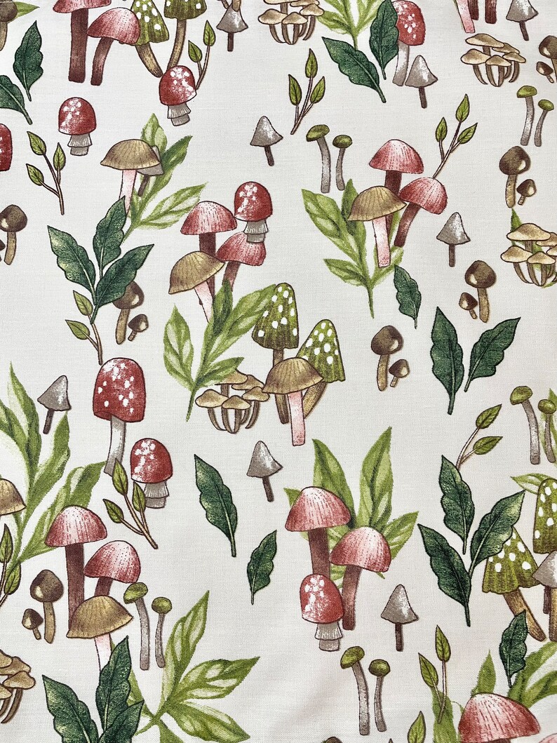 May include: A white fabric with a repeating pattern of red and brown mushrooms with green leaves. The mushrooms are of various sizes and shapes.
