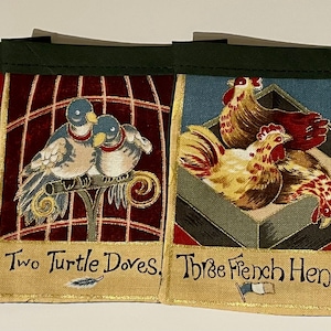 May include: A set of five fabric Christmas bunting flags with a red, green, and gold color scheme. Each flag features a different illustration from the Twelve Days of Christmas song: a partridge in a pear tree, two turtle doves, three French hens, four calling birds, and five golden rings. The flags are sewn together with a green ribbon.