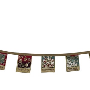 May include: A string of colorful fabric flags with various designs and text, hanging from a brown cord. The flags are decorated with images of animals, flowers, and geometric patterns.