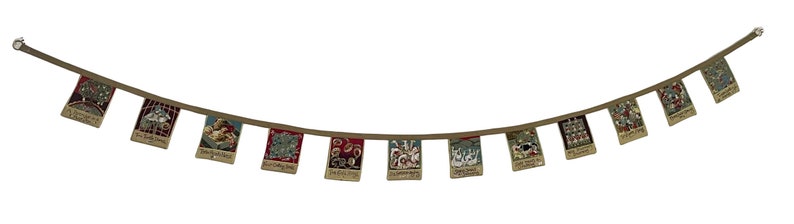 May include: A string of colorful fabric flags with various designs and text, hanging from a brown cord. The flags are decorated with images of animals, flowers, and geometric patterns.