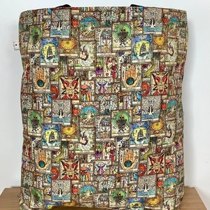 Op de afbeelding: Een beige tote bag met een kleurrijk patroon van tarotkaarten. De tas is gemaakt van stevige stof en heeft een groot hoofdvak.