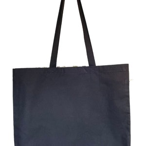 May include: A black canvas tote bag with two long black straps. The bag is empty.