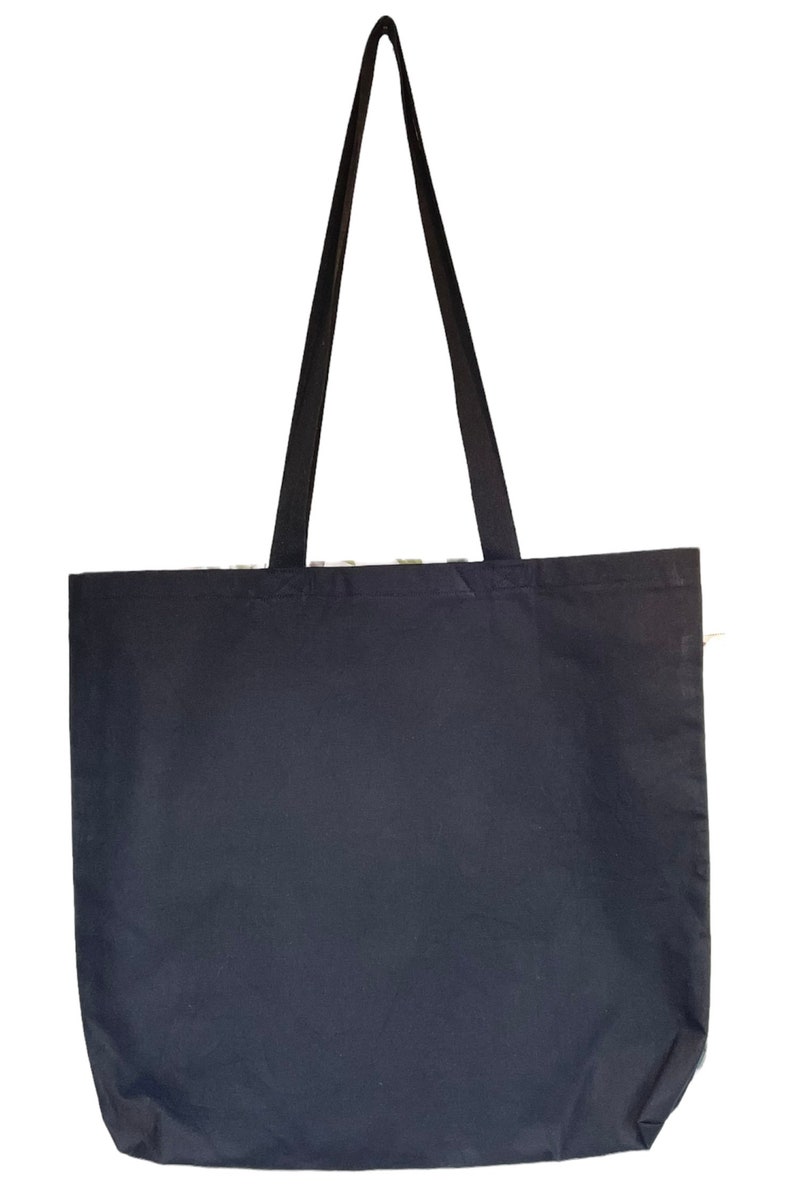 May include: A black canvas tote bag with two long black straps. The bag is empty.