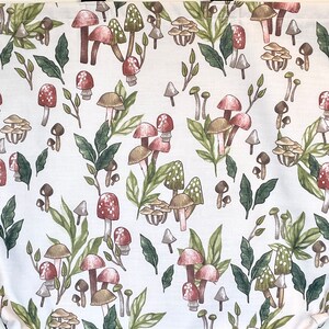 May include: White tote bag with a mushroom and leaf pattern. The mushrooms are red, brown, and white with green leaves.