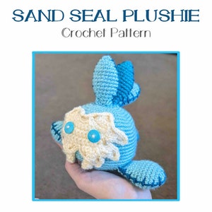 Op de afbeelding: Haakpatroon voor een blauwe en witte zandzeehond knuffel. De knuffel heeft een wit gezicht met twee blauwe knopen voor ogen.