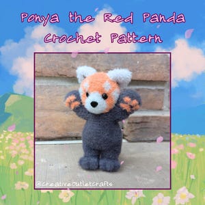 May include: A crocheted red panda plush toy with a grey body and orange and white face. The toy is standing on a brick surface with a green and blue background.
