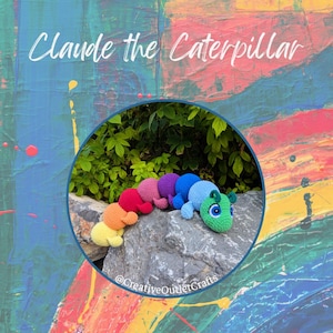 Könnte beinhalten: Ein handgefertigtes, farbenfrohes Häkel-Raupenspielzeug. Die Raupe ist in Gelb-, Orange-, Rot-, Rosa-, Lila-, Blau- und Grüntönen gehalten. Der Text "Claude the Caterpillar" steht über dem Spielzeug. Der Hintergrund ist ein abstraktes Gemälde.