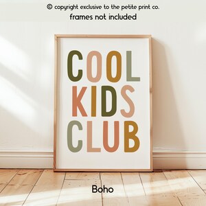 May include: A rectangular wall art print featuring the text COOL KIDS CLUB in a bold, sans-serif font. The letters are colored in muted shades of olive green, dusty pink, and mustard yellow against a plain white background.