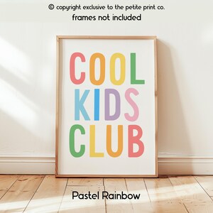 May include: A rectangular wall art print featuring the text COOL KIDS CLUB in large, sans-serif capital letters. Each letter is colored in a different pastel shade, including pink, orange, yellow, green, blue, and purple, set against a white background.