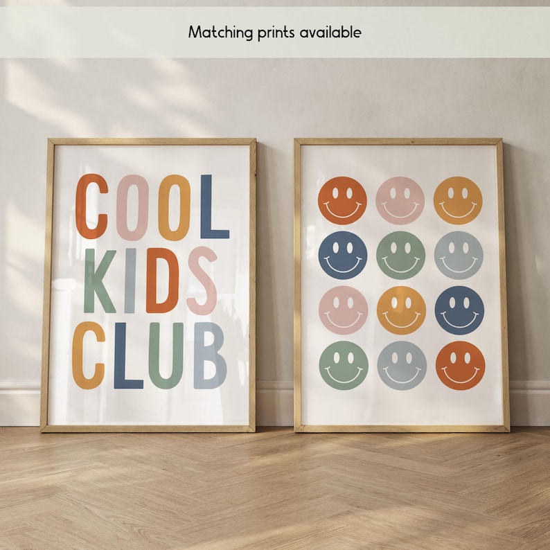 May include: Two framed wall art prints. The left print features the text "COOL KIDS CLUB" in multicolored block letters. The right print displays a grid of twelve colorful smiley face icons in shades of orange, pink, blue, and green.
