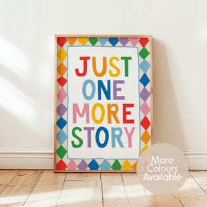 May include: A rectangular framed wall art print featuring the text JUST ONE MORE STORY in multicoloured capital letters. The border consists of a repeating pattern of colourful diamonds in red, orange, yellow, green, blue, and purple hues.
