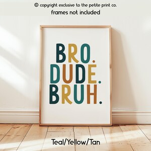 May include: A framed art print with the words "BRO. DUDE. BRUH." in teal, yellow, and tan colors. The text is centered on a white background. The bottom of the print reads "Teal/Yellow/Tan."