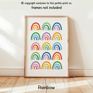 Op de afbeelding: Een ingelijste kunstafdruk met een patroon van kleurrijke regenbogen. De regenbogen zijn in een raster op een witte achtergrond geplaatst. Het woord "Rainbow" staat onderaan. De tekst "copyright exclusive to the petite print co. frames not included" staat bovenaan.