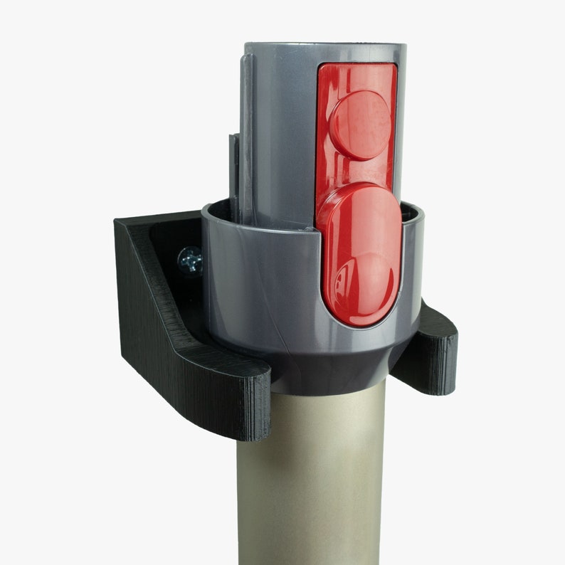 May include: A gray and black wall mount for a vacuum cleaner attachment. The attachment has two red buttons.