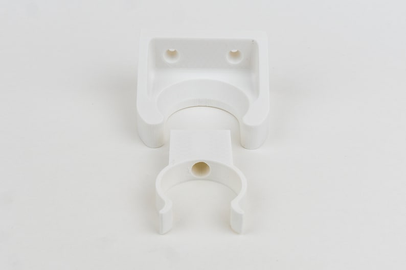 May include: White plastic wall mount with a U-shaped hook. The mount has two holes for screws.