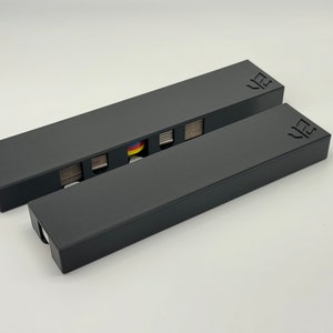 May include: Two black rectangular boxes with the word "VZ" printed on the top. The top box is open and has a deck of cards inside.