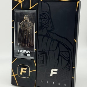 May include: A black and gold box with a gold F on the front. The box contains a gold-colored Darth Vader figurine inside a clear plastic case. The box has the text "FIGPIN" and "ULTRA" on it.