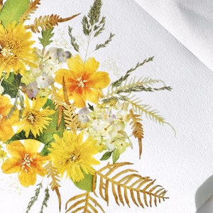 Pu&ograve; includere: Primo piano di una composizione floreale con fiori gialli e arancioni, foglie verdi e felci secche. I fiori sono disposti su una superficie bianca strutturata, creando una composizione naturale e artistica.