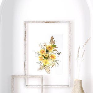Pu&ograve; includere: Una stampa floreale incorniciata con un bouquet di fiori gialli e fogliame secco. L'opera d'arte &egrave; esposta in una cornice di legno sbiancato. L'immagine &egrave; su sfondo bianco, con un arco decorativo e un vaso con piante secche.