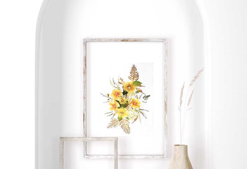 Pu&ograve; includere: Una stampa floreale incorniciata con un bouquet di fiori gialli e fogliame secco. L'opera d'arte &egrave; esposta in una cornice di legno sbiancato. L'immagine &egrave; su sfondo bianco, con un arco decorativo e un vaso con piante secche.