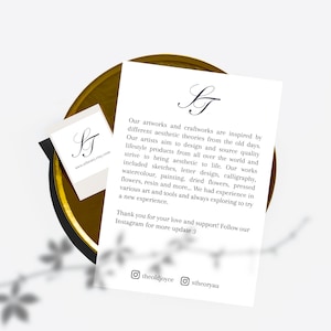 Pu&ograve; includere: Una carta bianca e un biglietto da visita con il logo "ST" in corsivo nero sono su un vassoio color oro. La carta pi&ugrave; grande ha un testo sull'arte e il design. Il biglietto da visita ha l'indirizzo del sito web.