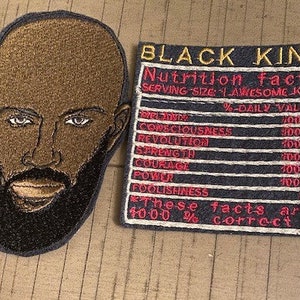 Peut inclure: Deux patchs brodés, l'un avec un portrait noir et brun d'un homme barbu et l'autre avec le texte "BLACK KING" et un tableau de valeurs nutritionnelles avec le texte "1000% correct".
