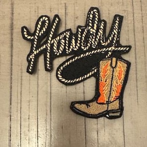 May include: Embroidered patch featuring the word "Howdy" in a rope-like font above a cowboy boot. The boot has orange and yellow flame-like designs on a tan background, outlined in black.