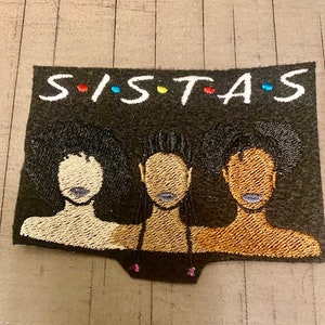 May include: Embroidered patch with the text "SISTAS" in white with colorful dots between each letter. Three black women with different hairstyles are depicted below the text.