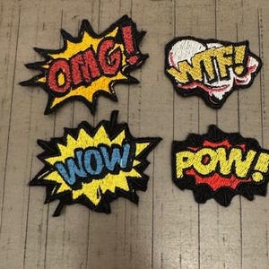 May include: Four colorful iron-on patches with comic book style speech bubbles. The patches say "OMG!" in red and yellow, "WTF!" in red and white, "WOW!" in blue and yellow, and "POW!" in red and yellow.